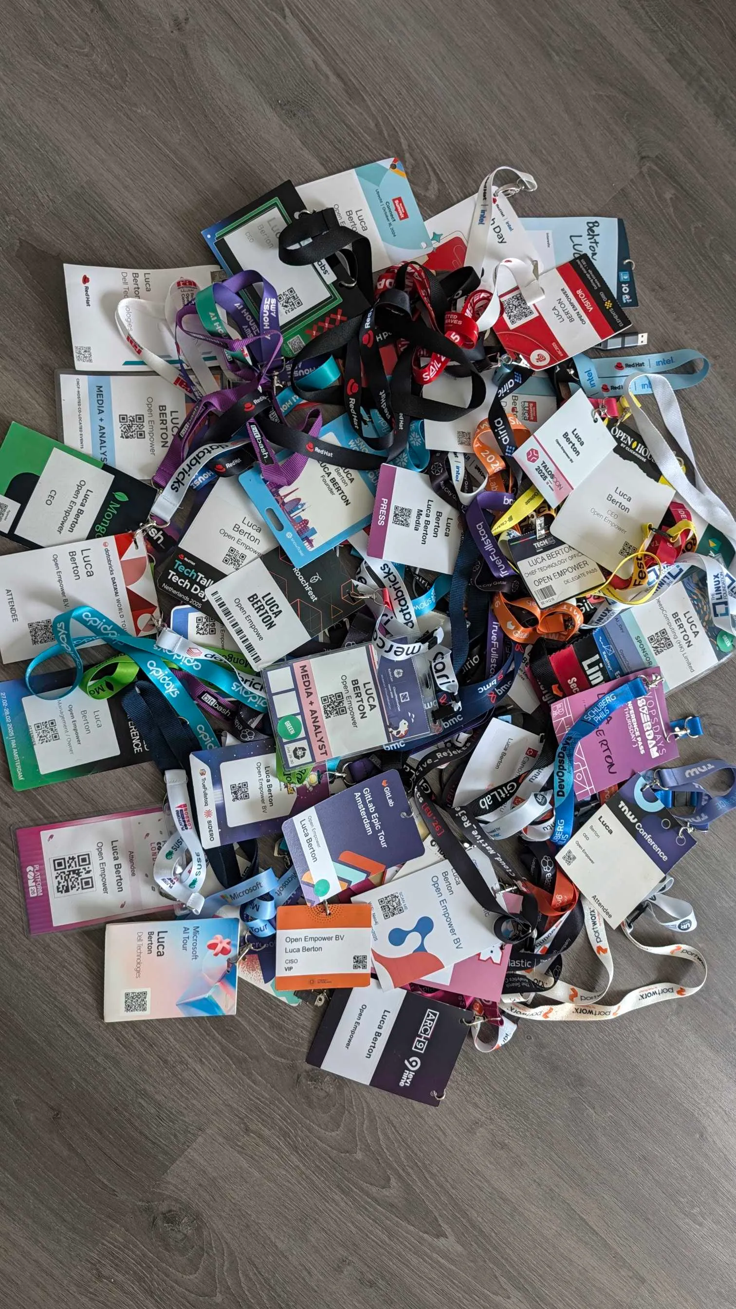 Conference lanyards and badges scattered across a grey wood floor
