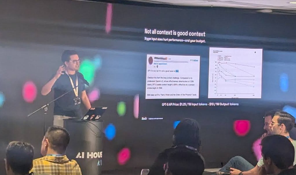 A speaker at the AI House lectern next to a slide titled Not all context is good context: bigger input sizes hurt performance and your budget, with a long-context chart and the line GPT-5 API Price: $1.25 / 1M input tokens â $10 / 1M output tokens