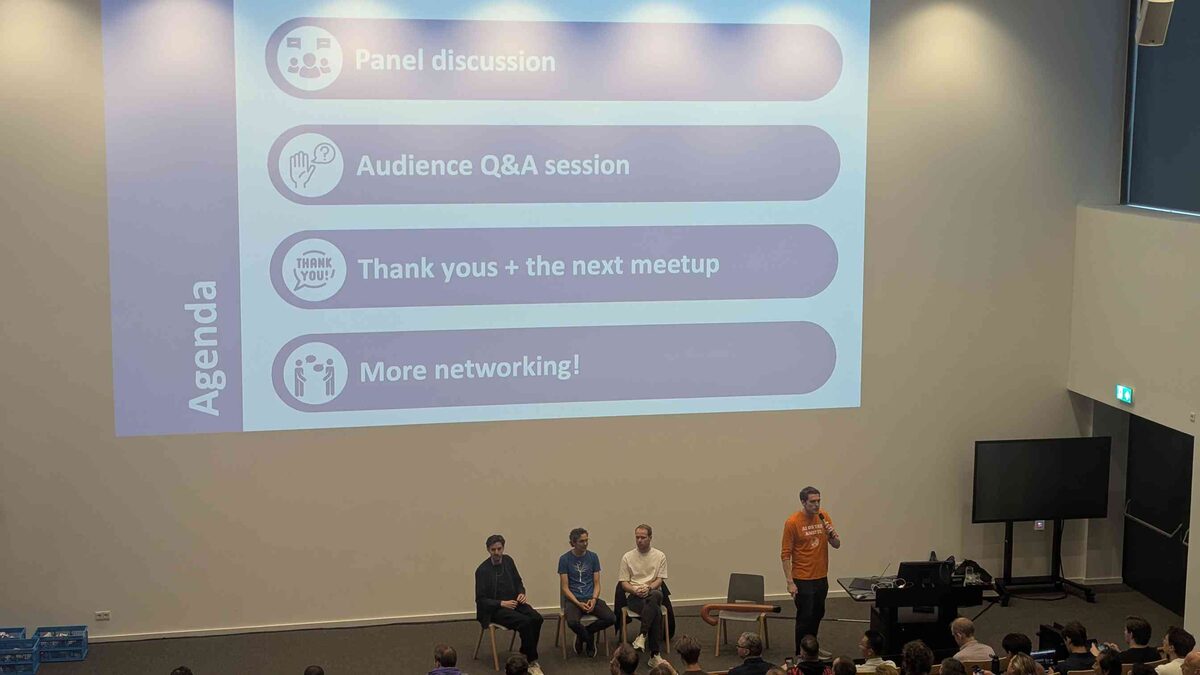 Panel discussion on stage — agenda slide showing panel, Q&A, and networking