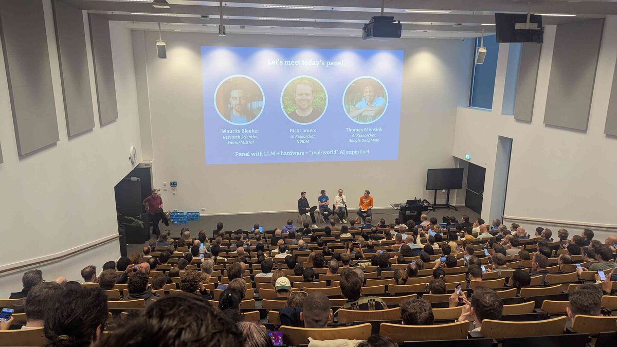 Wide shot of packed auditorium with panel introduction slide