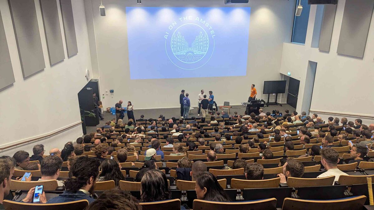 Packed auditorium from the back — hundreds of attendees, AI on the Amstel logo on screen