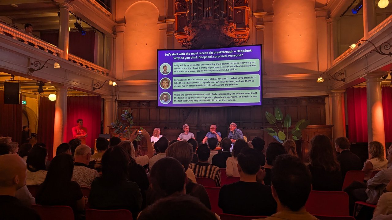 Panel on stage under a slide titled with the DeepSeek question and three answers