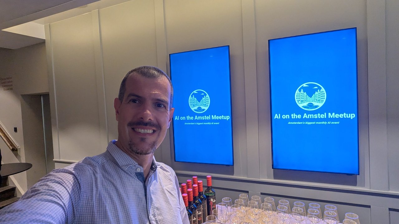 Luca Berton taking a selfie in front of two screens showing the AI on the Amstel Meetup logo