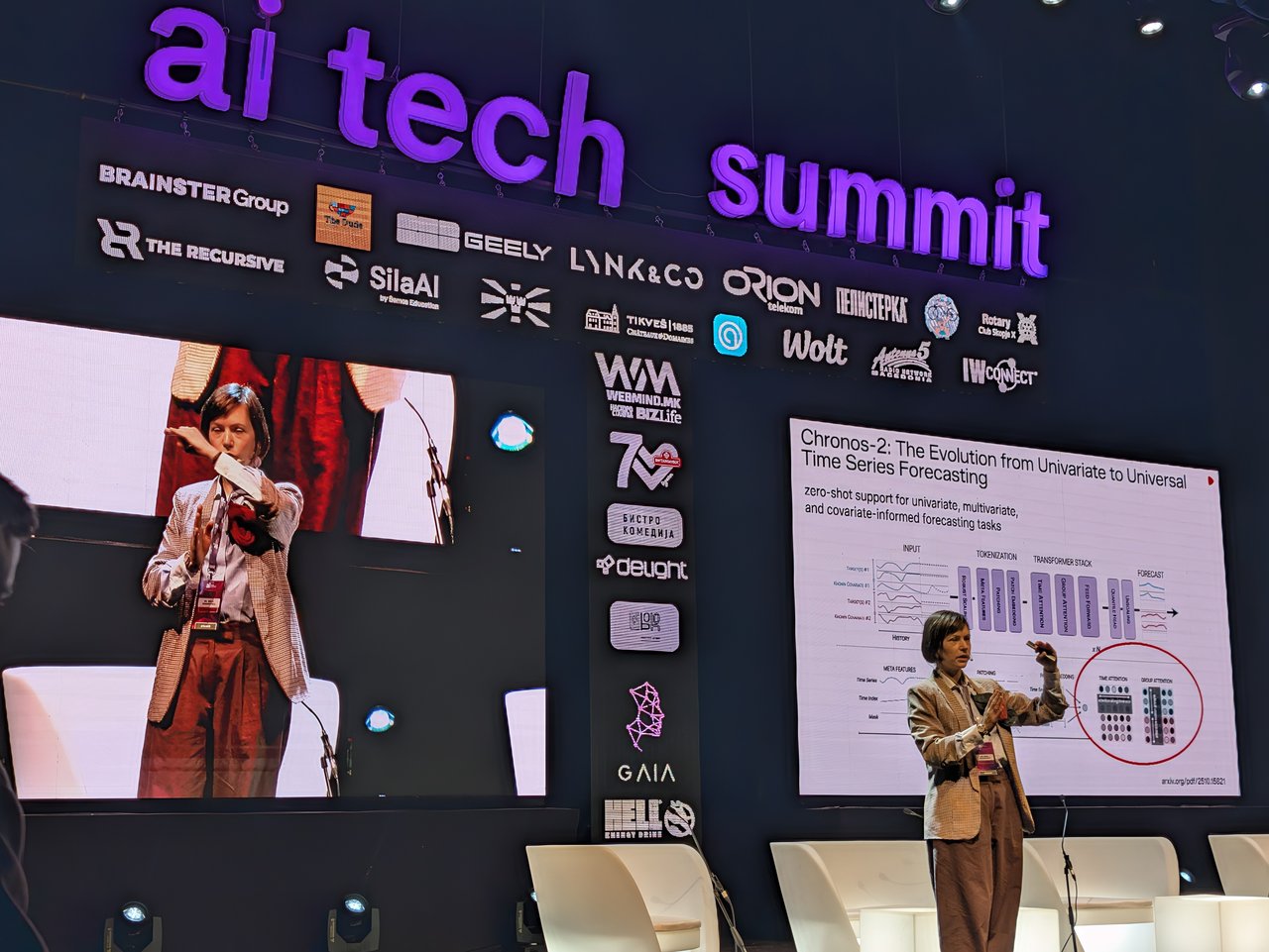 Dr. Irena Bojarovska on the Main Stage next to a slide titled Chronos-2: The Evolution from Univariate to Universal Time Series Forecasting, with an architecture diagram