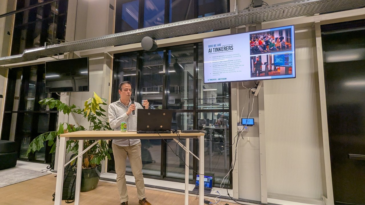The AI Tinkerers Amsterdam host introducing the community in front of the Who We Are slide