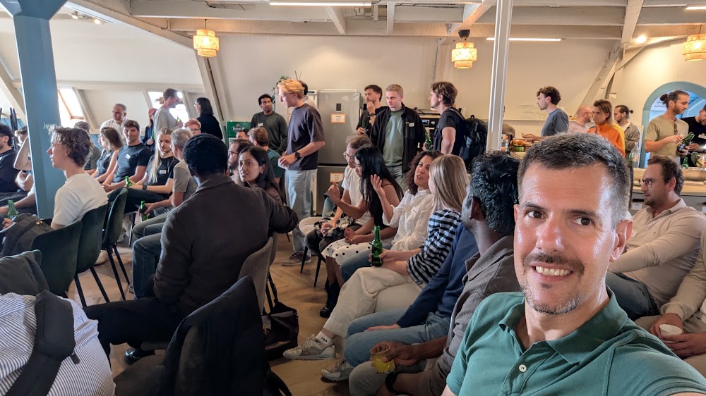 Attendees mingling with drinks in the bright loft-style main room at StartDock