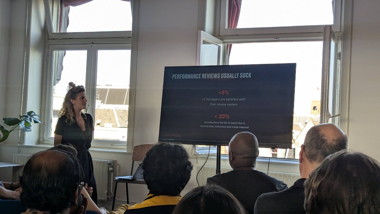 Pandria speaker presenting the "Performance reviews usually suck" slide with under 5% and under 33% statistics
