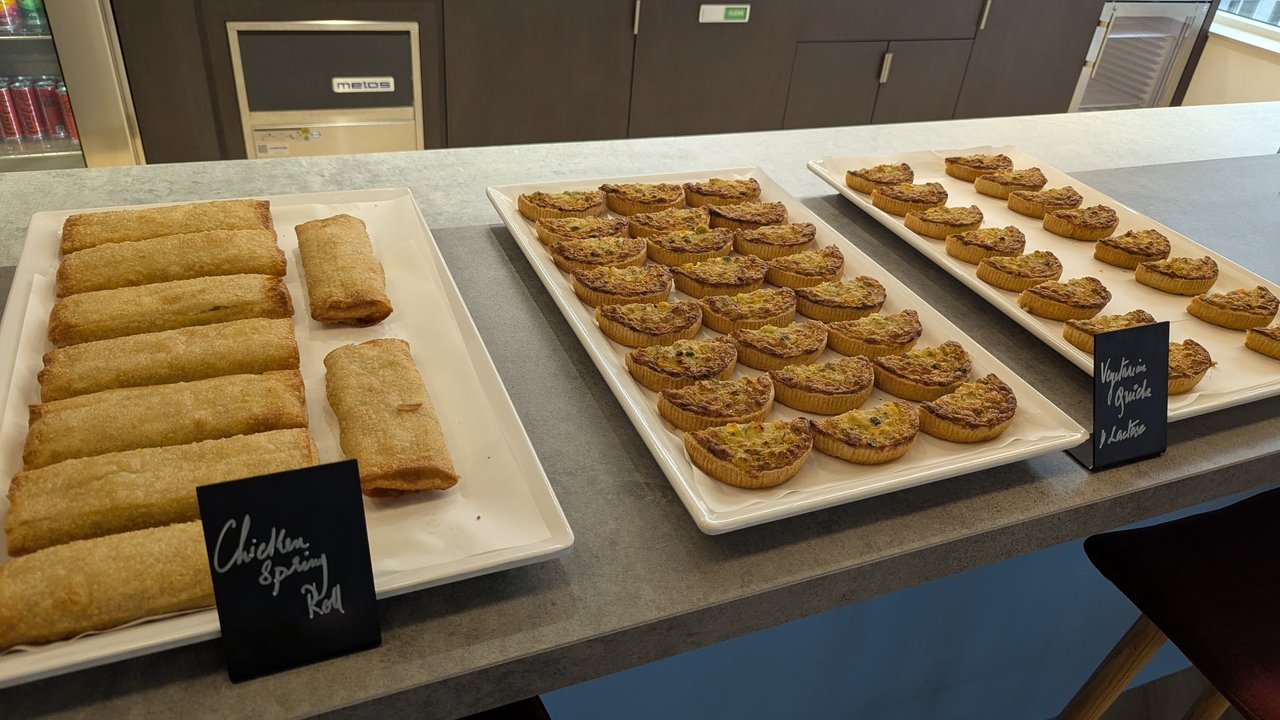 Tray of savoury pastries and snacks with small name cards on a counter at the Snowflake Experience Centre