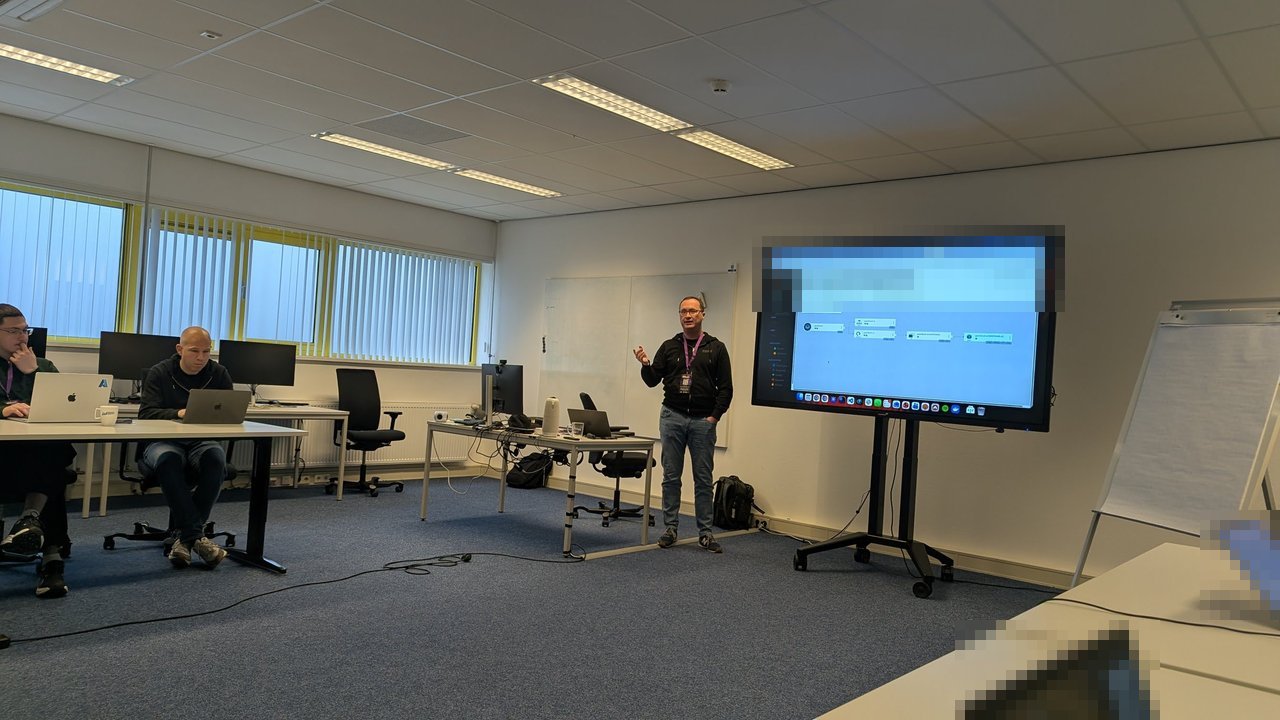 A BitBash 2026 workshop room with a trainer standing next to a large screen showing an Argo CD application view