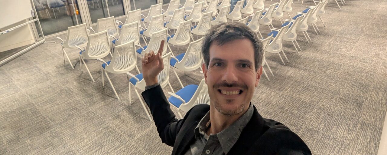 Luca Berton smiling in the empty meetup room at Dell Technologies in London before the Ansible meetup, with rows of white chairs behind him
