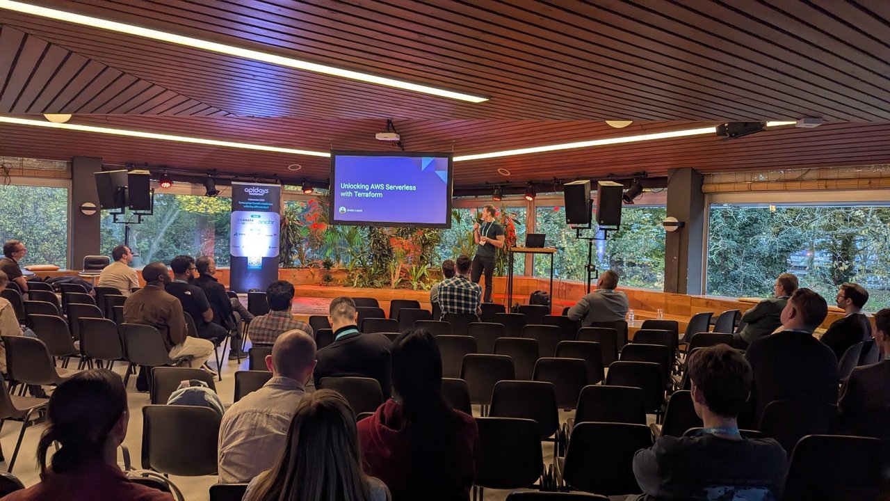 The title slide Unlocking AWS Serverless with Terraform by Andre Lopes on the room screen, with a sparse audience in the afternoon