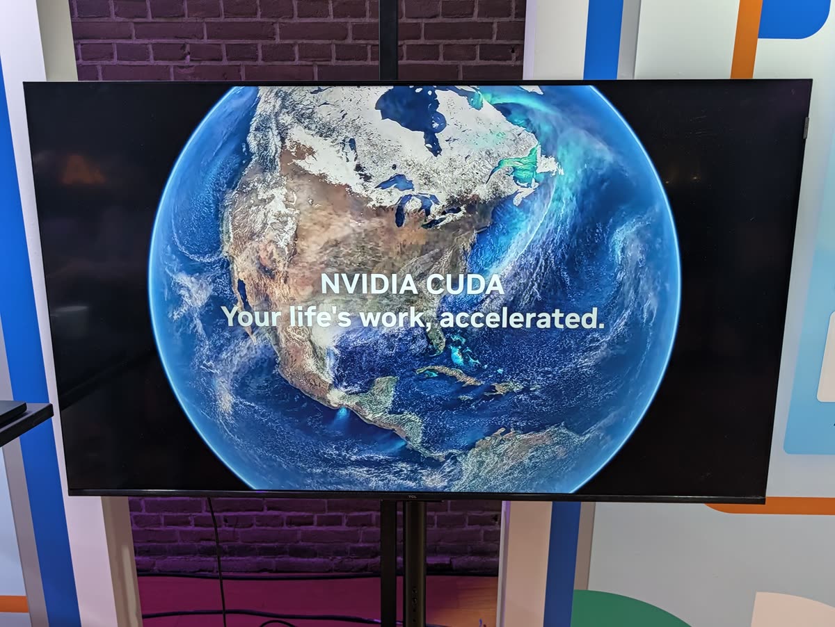 A TV screen on a stand in front of a brick wall showing the Earth and the words NVIDIA CUDA, Your life’s work, accelerated