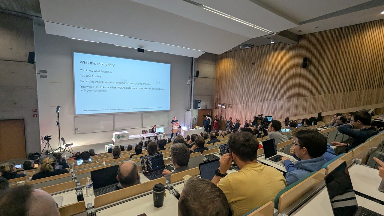 A "Who this talk is for?" slide in the main auditorium at CfgMgmtCamp 2025 in Ghent: people who know and use Ansible, create Ansible content, and want to use ARA personally and with colleagues