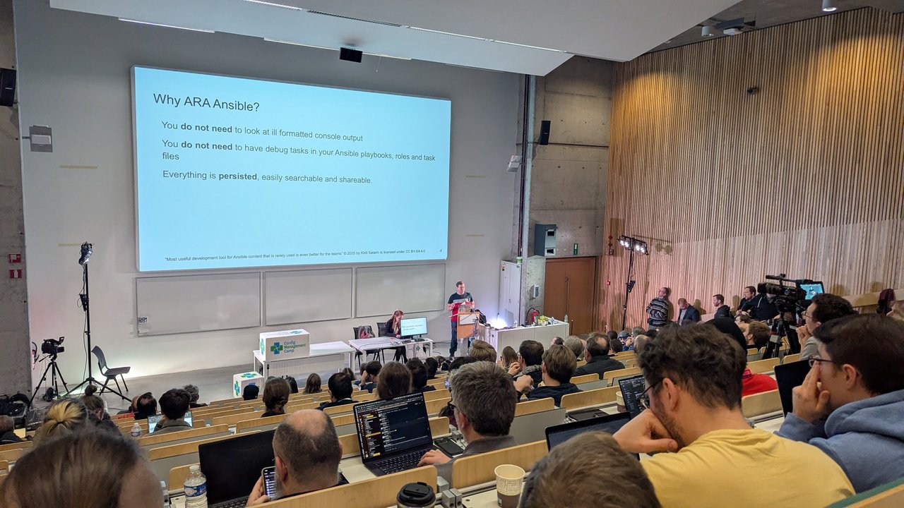 A "Why ARA Ansible?" slide in the main auditorium at CfgMgmtCamp 2025 in Ghent: no need to read badly formatted console output or add debug tasks, and everything is persisted, easily searchable and shareable