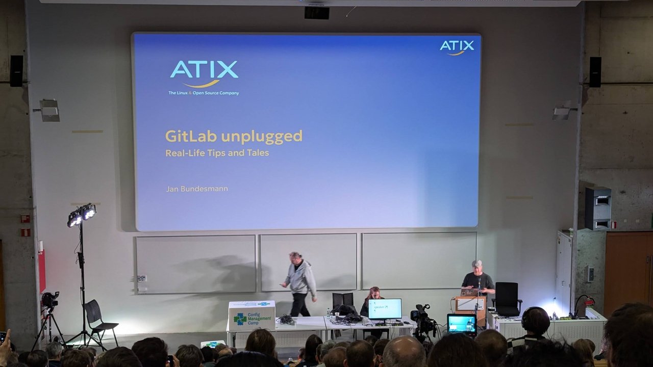 The ATIX title slide GitLab unplugged, Real-Life Tips and Tales, by Jan Bundesmann, on the main stage at CfgMgmtCamp 2025
