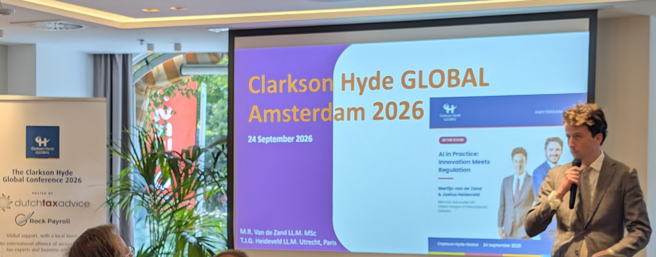 Projected slide reading Clarkson Hyde GLOBAL Amsterdam 2026, 24 September 2026, next to a roll-up banner for The Clarkson Hyde Global Conference 2026 hosted by dutchtaxadvice and Rock Payroll