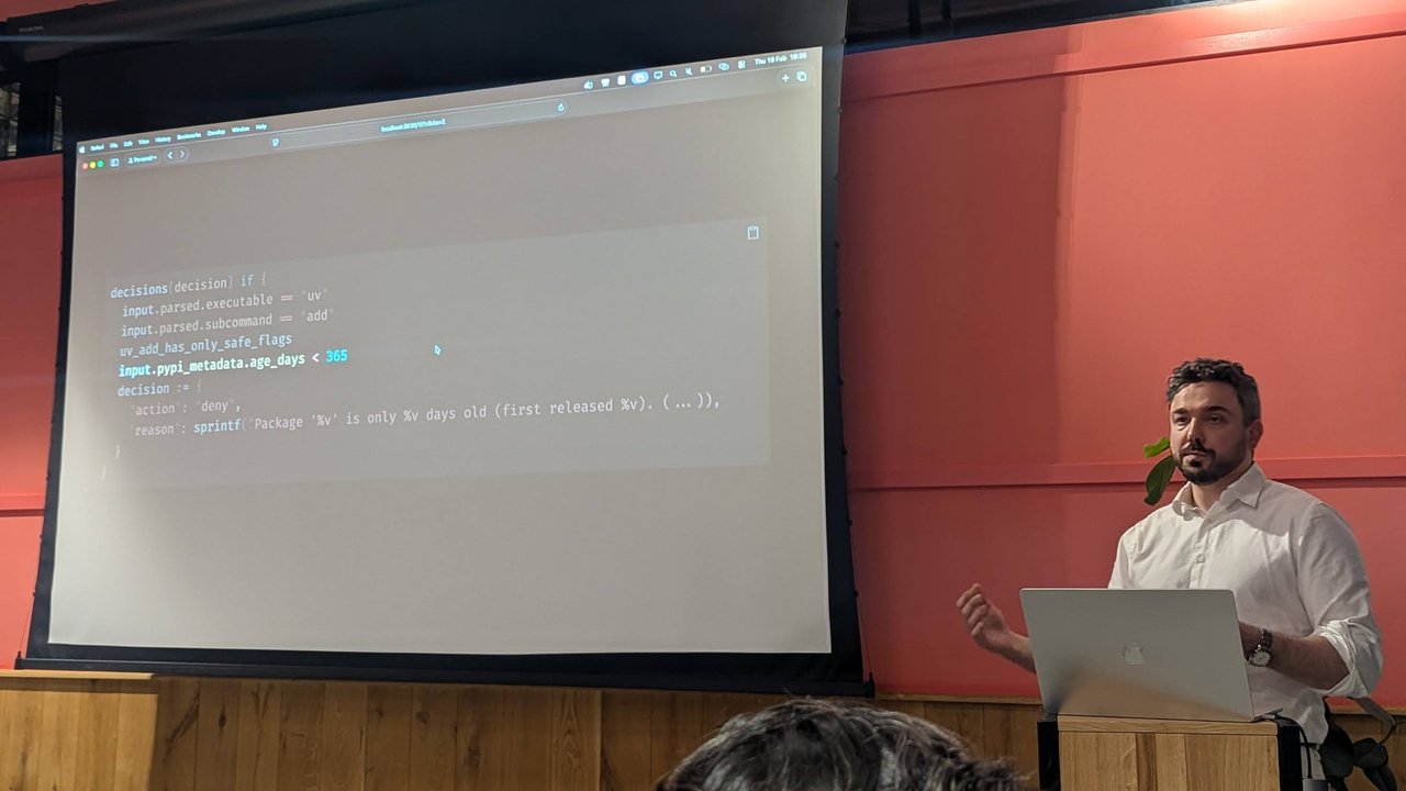 A slide at Claude Code Meetup Amsterdam with a Rego-style rule that denies uv add when input.pypi_metadata.age_days is under 365, with a sprintf reason giving the package age and first release date