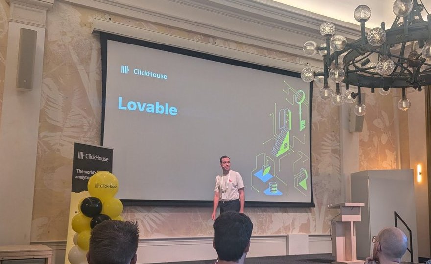 The Lovable speaker on stage at ClickHouse Open House Amsterdam, under a chandelier, with the Lovable title slide on the main screen