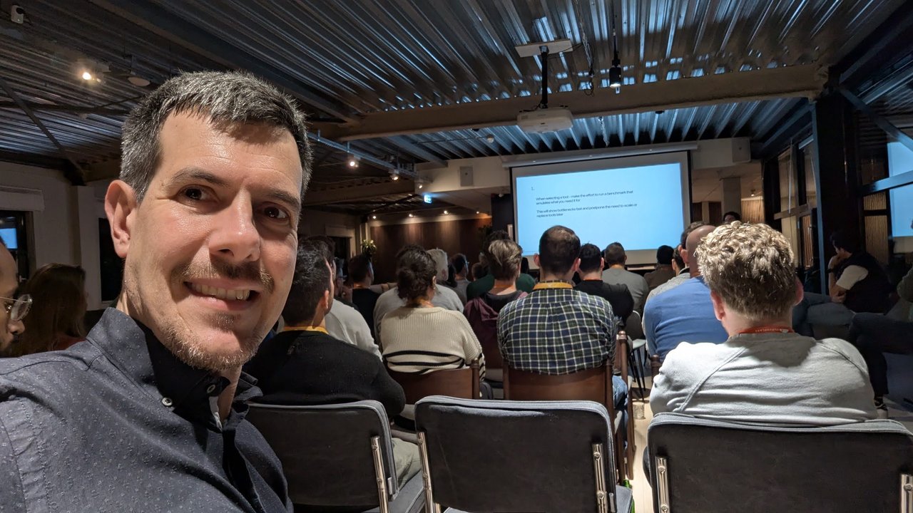Luca Berton in the audience at the Cloudflare Founders & Developers Meetup at Wicked Grounds, Amsterdam, with a slide on benchmarking tools on the screen