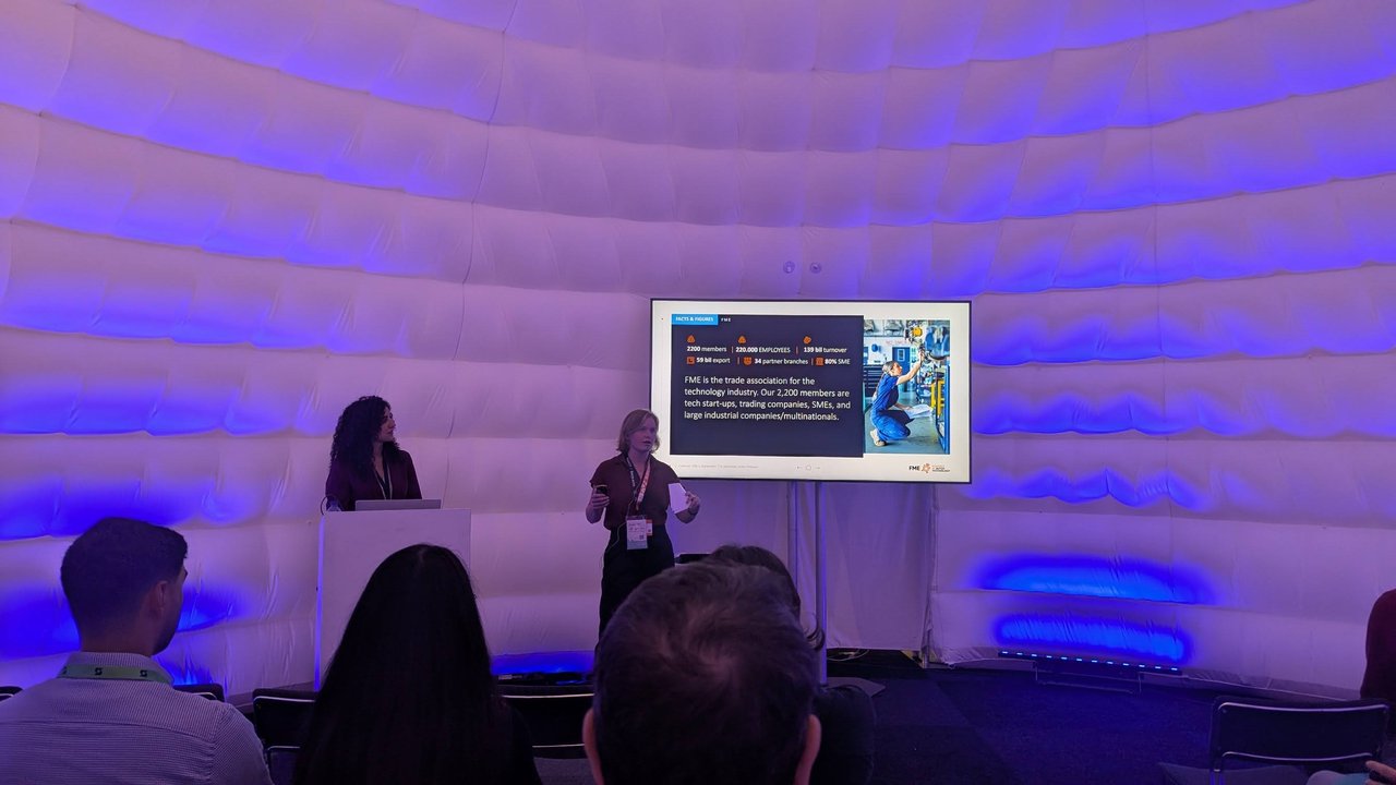 An FME speaker presenting the Facts and Figures slide in the dome theatre, listing 2200 members, 220,000 employees, 139 billion turnover, 59 billion export, 34 partner branches and 80% SME