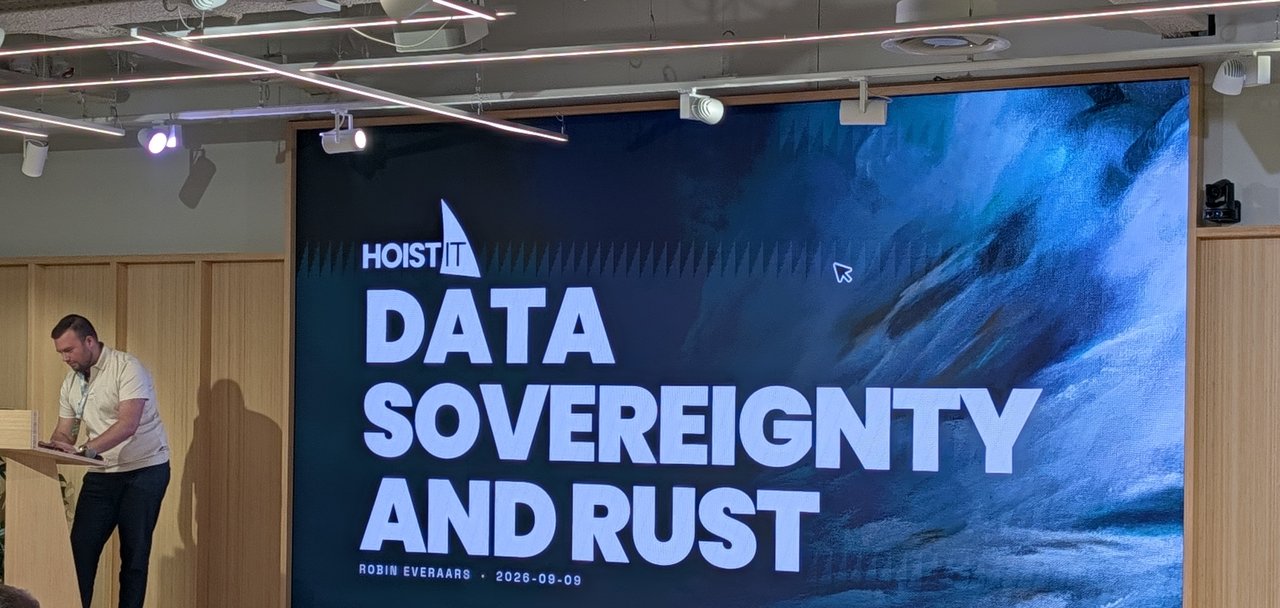 Robin Everaars at the podium next to his HoistIT title slide "Data Sovereignty and Rust", dated 2026-09-09