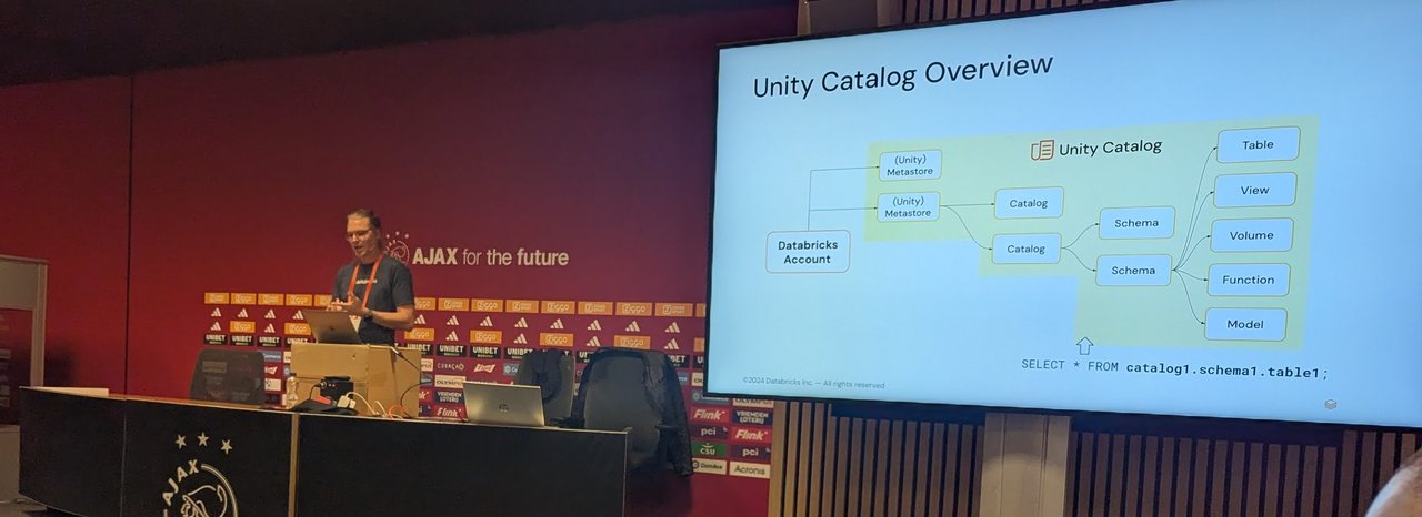 Slide: Unity Catalog Overview, showing a Databricks account, metastores, catalogs, schemas and tables, views, volumes, functions and models