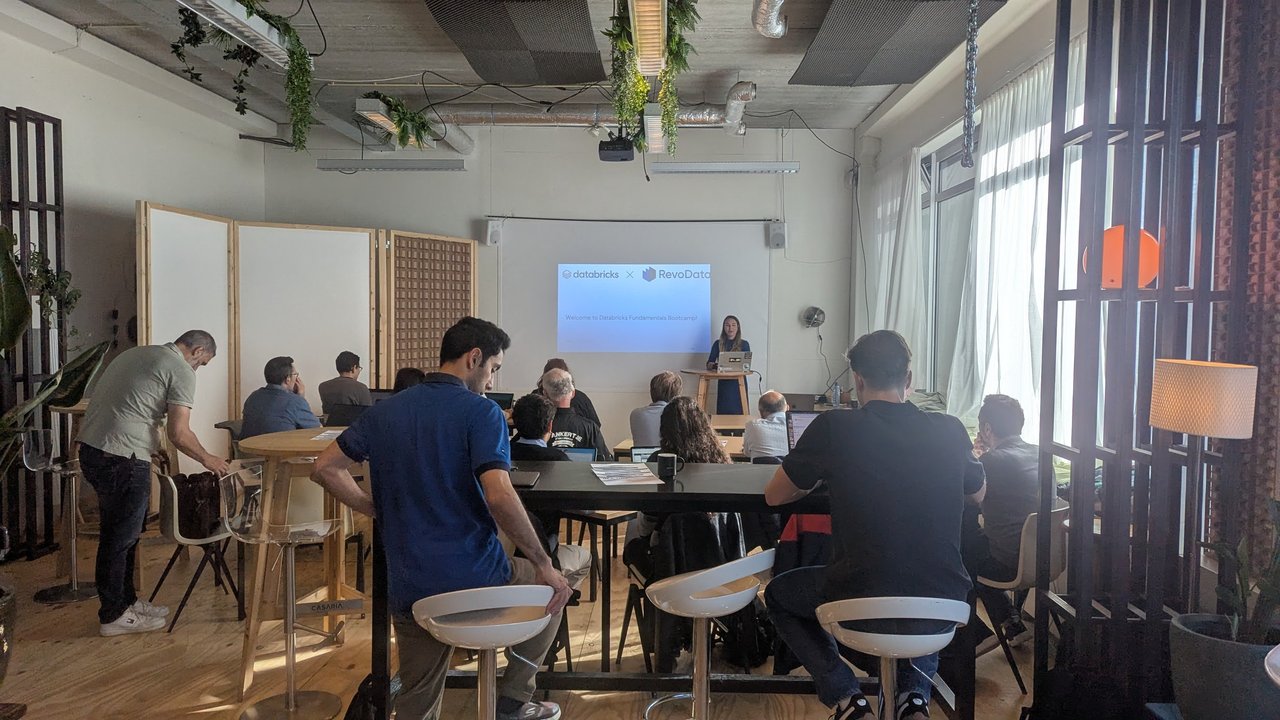 Small training room with attendees at tables facing a screen showing Welcome to Databricks Fundamentals Bootcamp