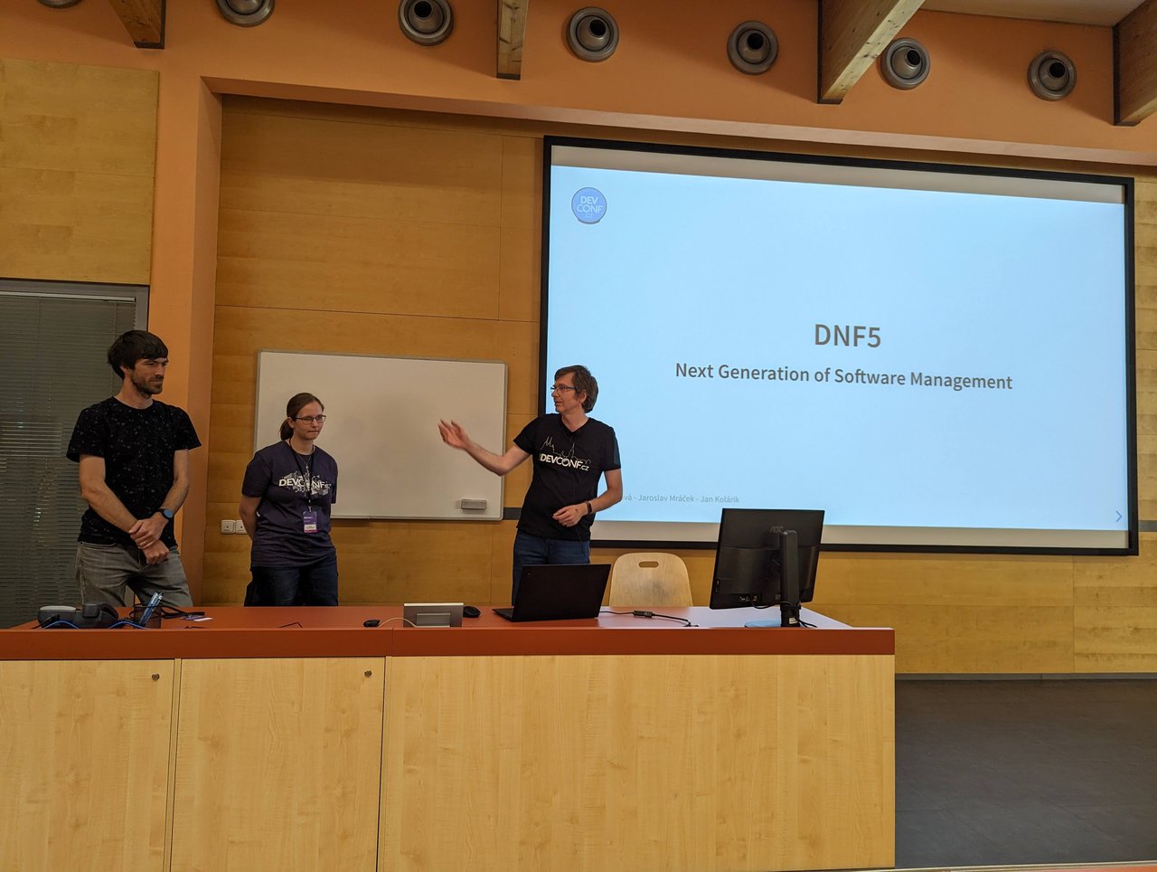 The three DNF5 presenters on stage at DevConf.CZ 2023 in front of the title slide "DNF5: Next Generation of Software Management"