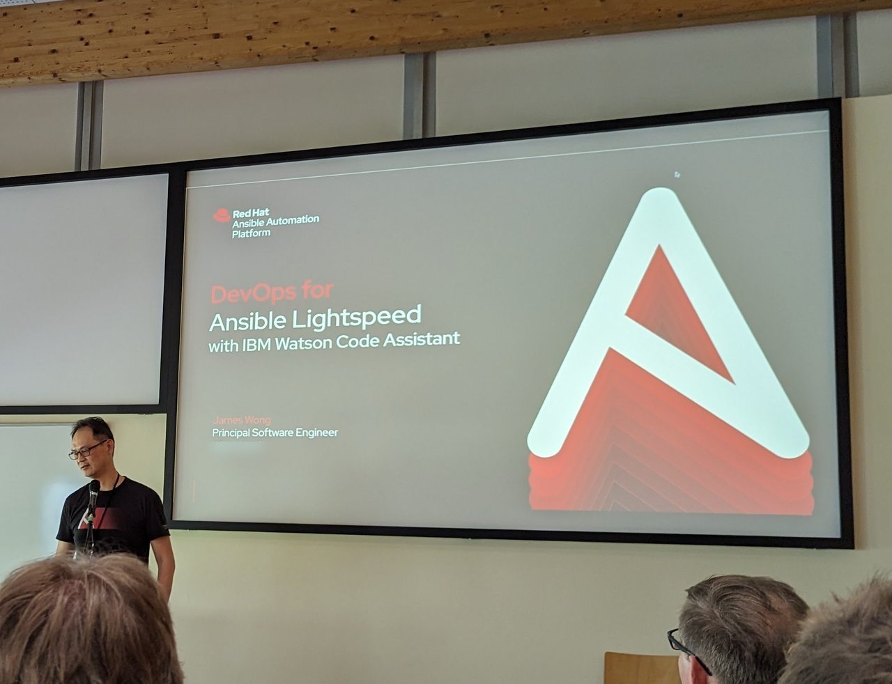 Title slide "DevOps for Ansible Lightspeed with IBM Watson Code Assistant" at DevConf.CZ 2023, with the speaker standing beside the screen