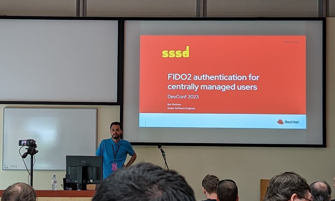 Title slide "sssd: FIDO2 authentication for centrally managed users, DevConf 2023" with the speaker at the front of the lecture room