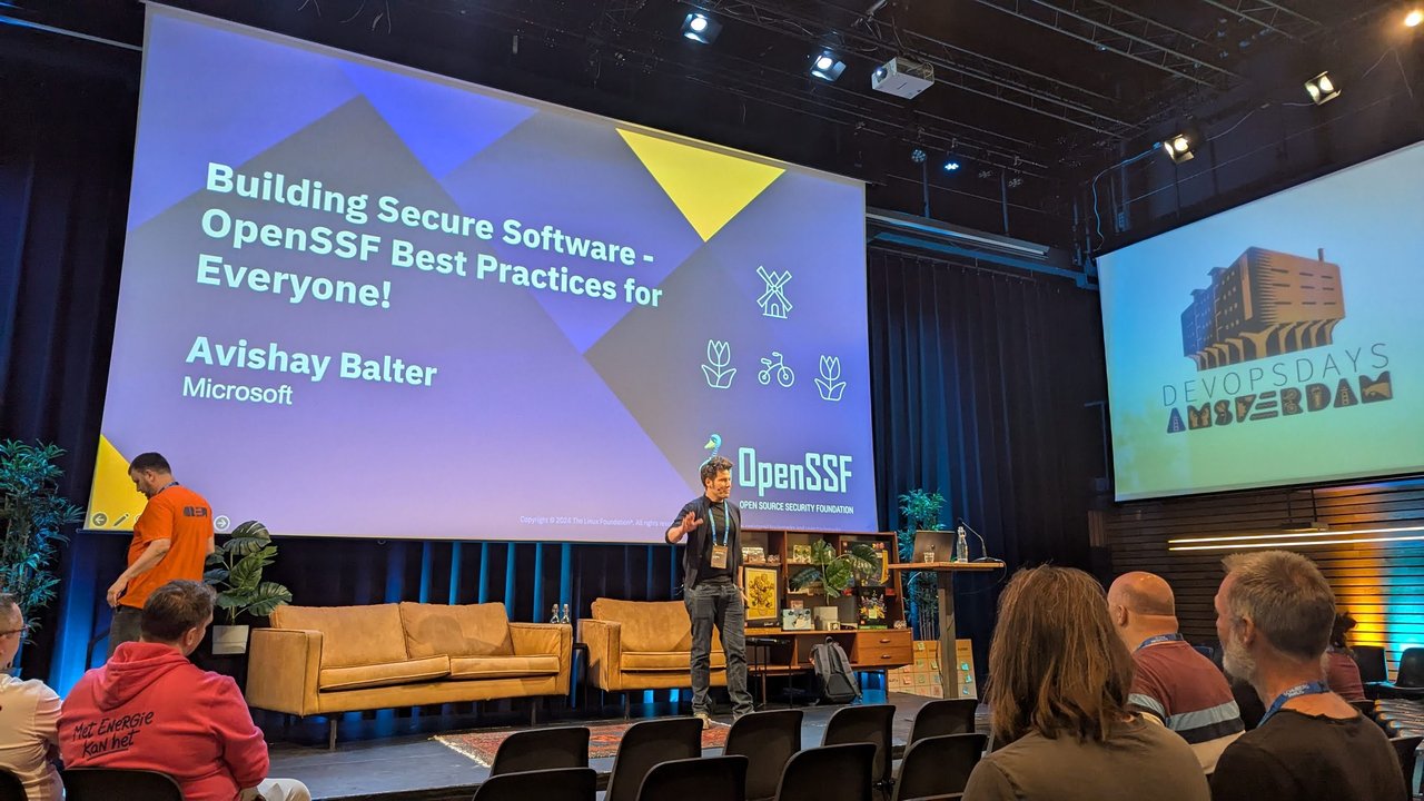 Title slide of Building Secure Software - OpenSSF Best Practices for Everyone by Avishay Balter of Microsoft, with the speaker on stage at DevOpsDays Amsterdam