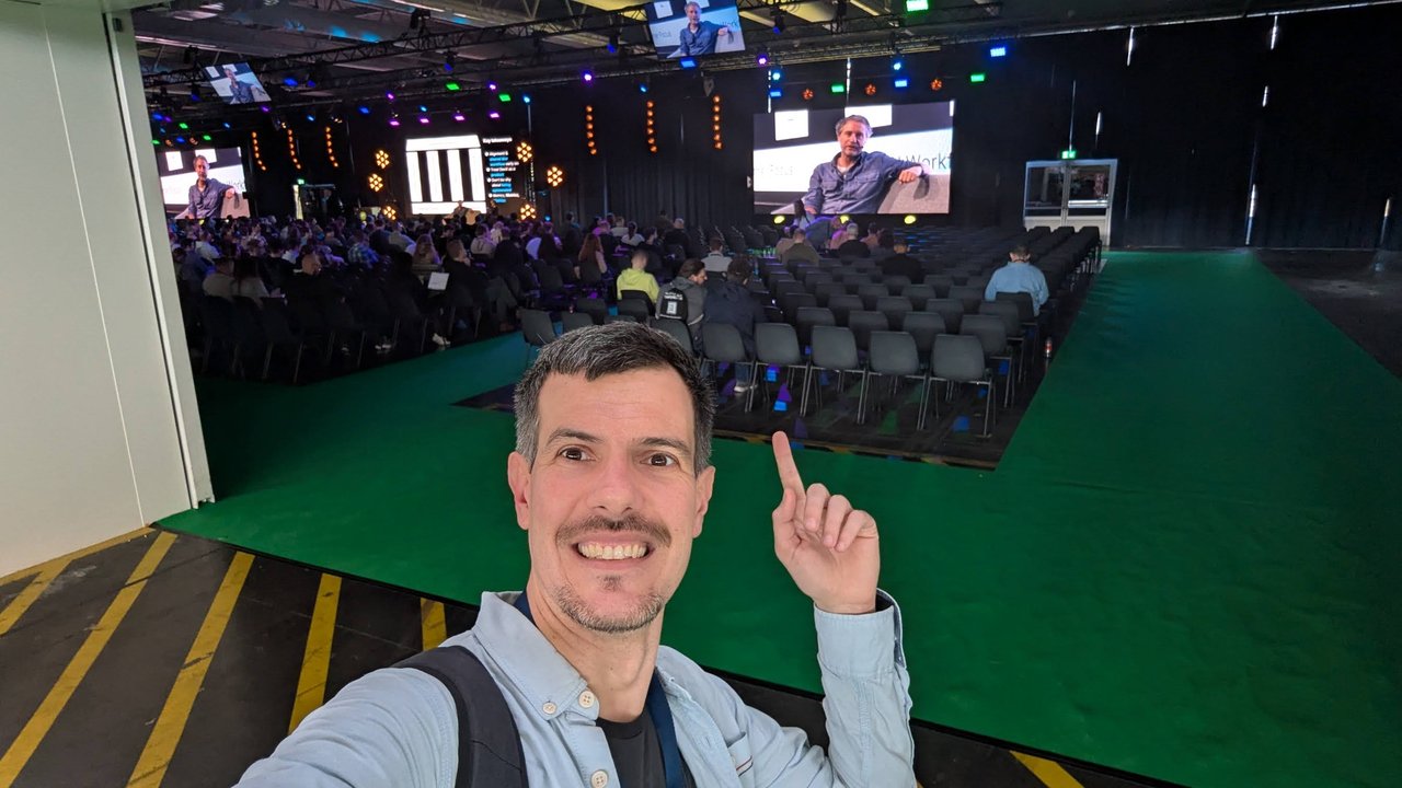 Luca Berton in front of the DevWorld 2025 main stage at RAI Amsterdam, with the speaker shown on large screens