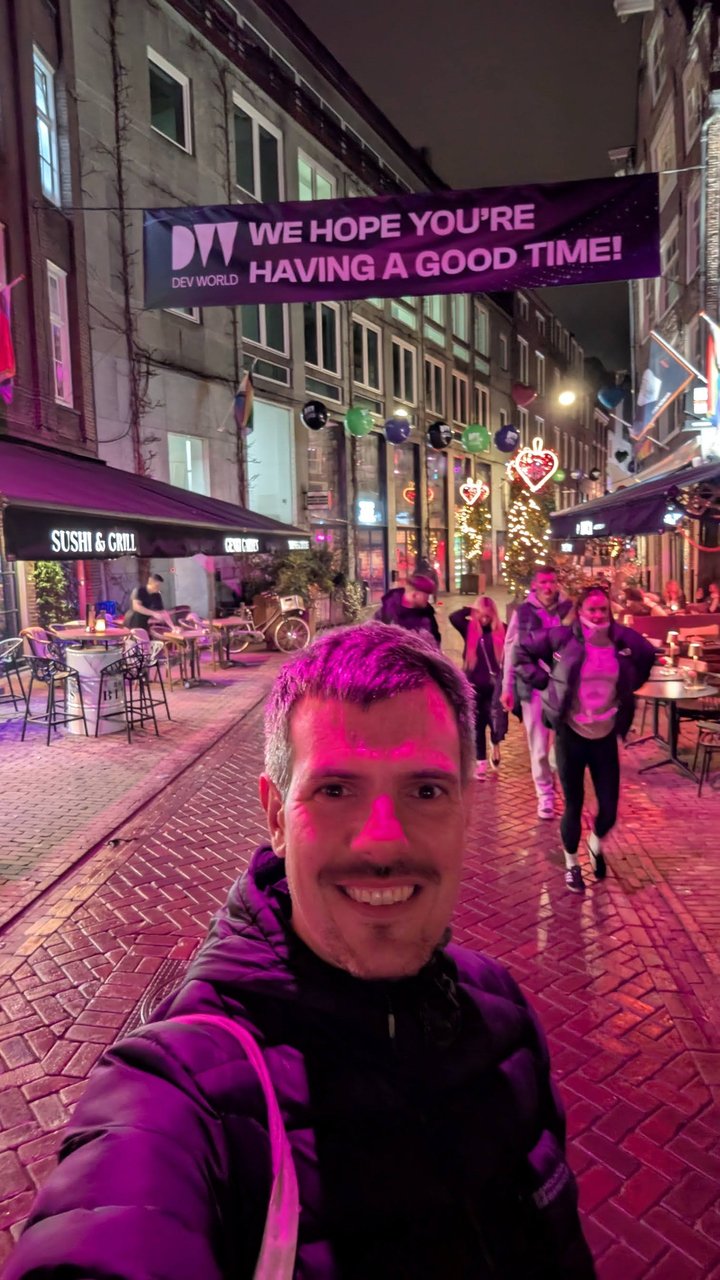 Luca Berton under a DevWorld banner reading We hope you're having a good time, hung across a street at night