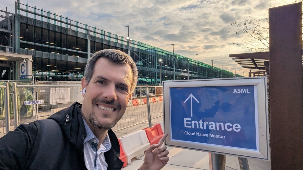 Luca Berton pointing at a blue ASML sign reading Entrance, Cloud Native Meetup, outside the venue in Veldhoven