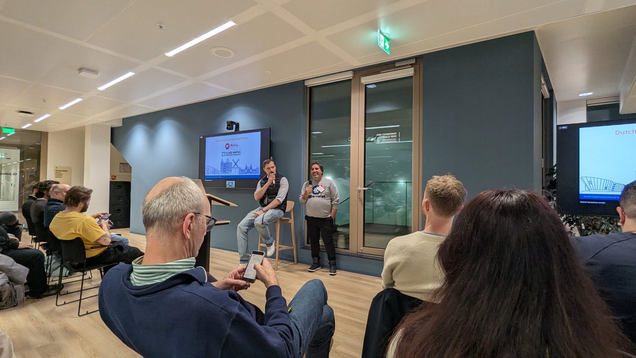 Two organisers opening the Dutch Kubernetes/Cloud Native Meetup in front of the title slide with the Meetup and CNCF logos