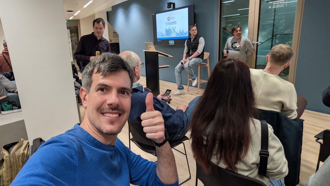 Luca Berton taking a selfie in the meetup room at Palo Alto Networks Amsterdam, with attendees seated in front of the screens