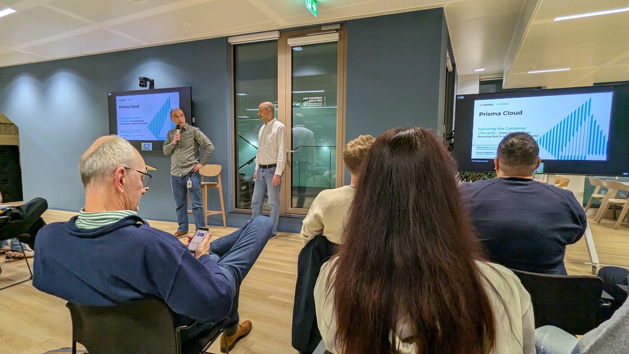 Milan Krstic and Goran Bogojevic presenting Securing the Container Lifecycle, From Dockerfile to Running Pod in a Kubernetes Cluster, with the Prisma Cloud title slide on two screens