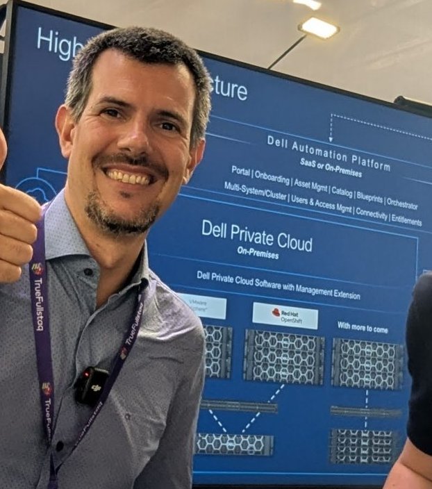 Luca Berton in front of a Dell booth screen showing a high level architecture: Dell Automation Platform (SaaS or on-premises) above Dell Private Cloud on-premises, with VMware and Red Hat OpenShift boxes over rows of servers