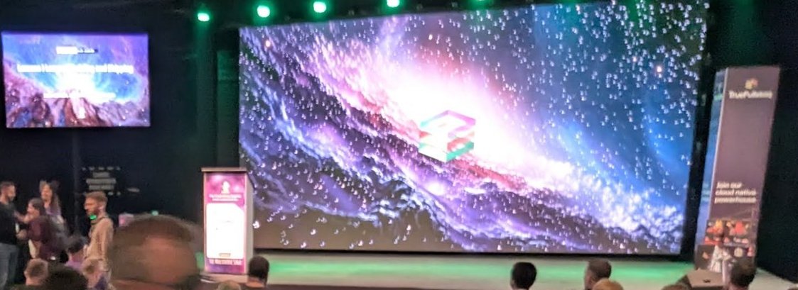 Stage of the main hall at EDGECASE 2025: a wall-sized LED screen showing a galaxy and a smaller screen with the session title, before the next talk