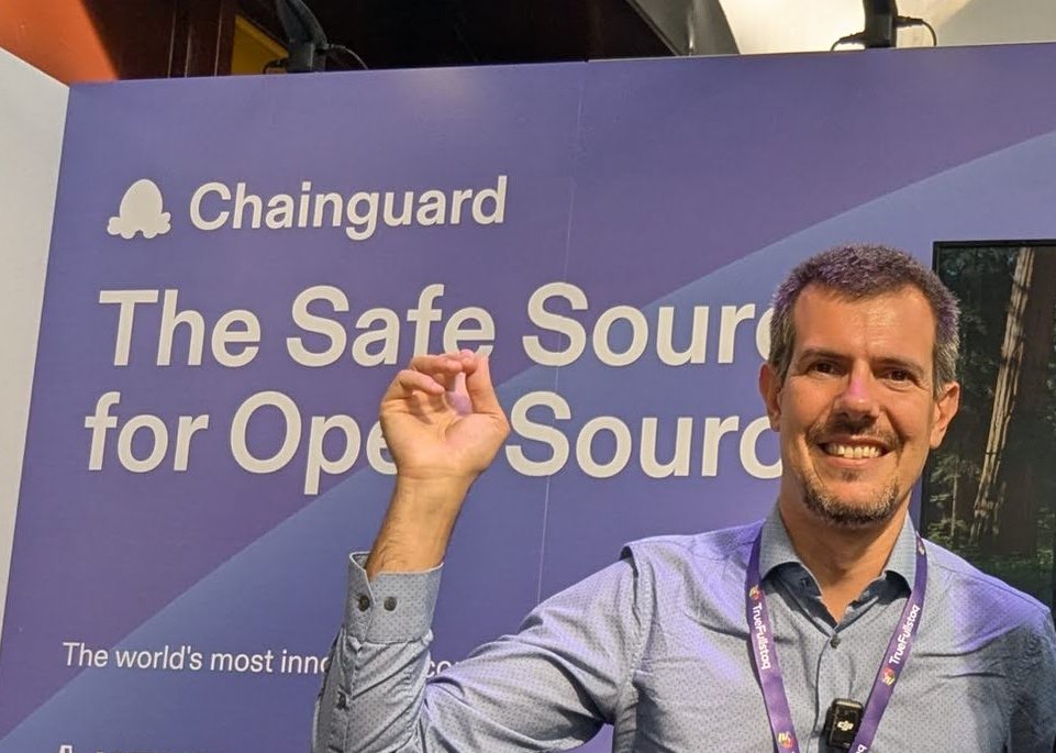 Luca Berton at the Chainguard booth at EDGECASE 2025, in front of a purple wall reading Chainguard, The Safe Source for Open Source