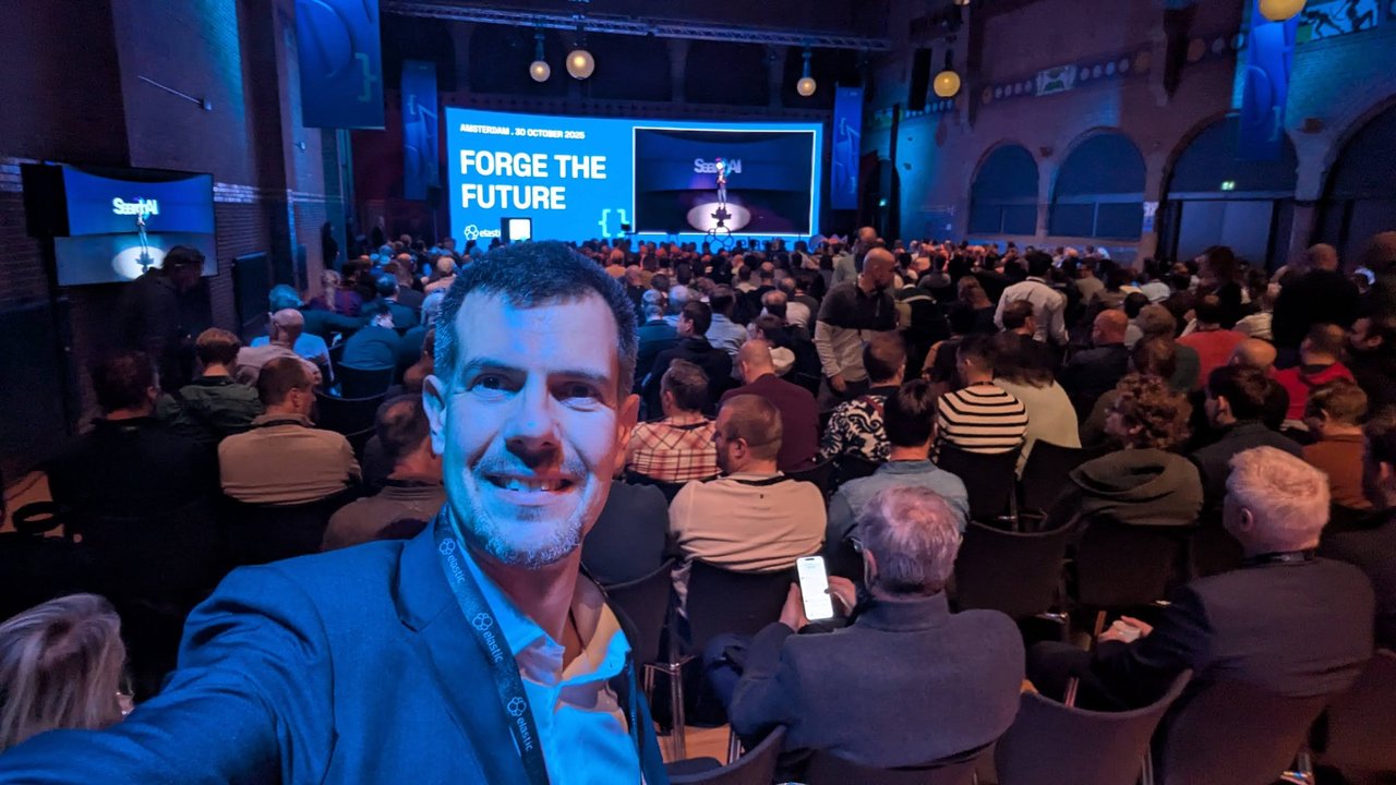 Luca Berton taking a selfie in the packed ElasticON Amsterdam keynote hall, with the Forge the Future and Search AI screens behind him