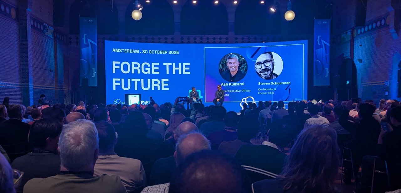 Ash Kulkarni and Steven Schuurman seated on the ElasticON Amsterdam stage, with their names and titles on the Forge the Future screen