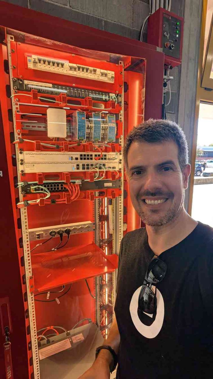 The red equipment cabinet — MCBs, terminal blocks, network switches, and patch panels inside