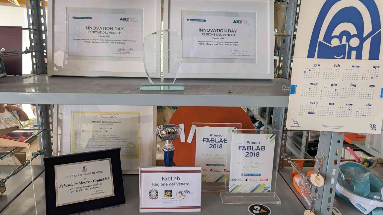 The CrunchLab awards wall — Innovation Day certificates, FabLab trophies, and a plaque from the Comune di San Donà di Piave