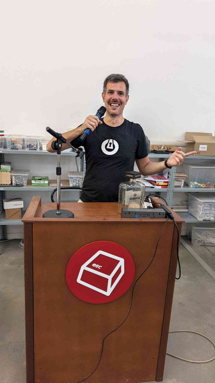 Speaking at the ESC podium — gesturing with the mic in hand, the workshop space behind me