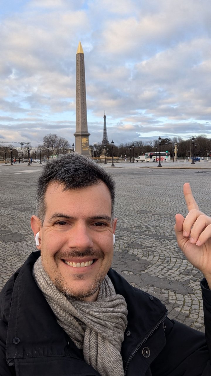 Luca Berton pointing up at the obelisk in Place de la Concorde with the Eiffel Tower in the distance