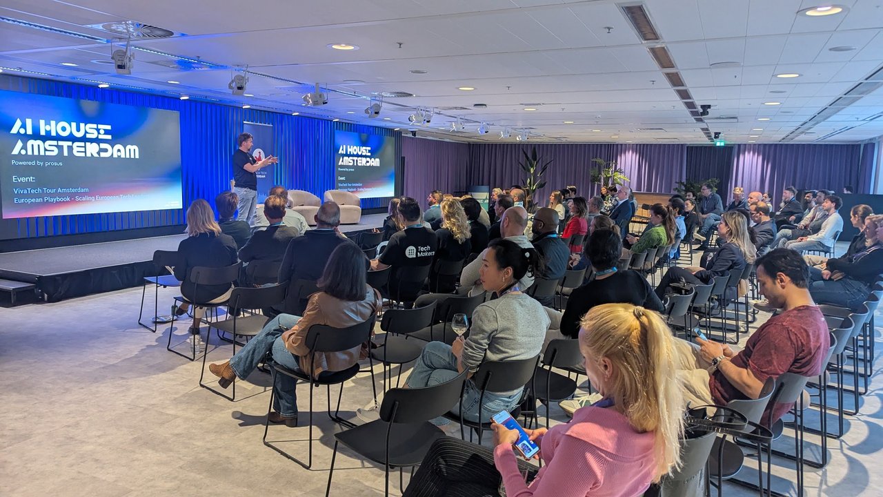 Wide view of the AI House Amsterdam main hall with rows of attendees facing the stage and a screen reading VivaTech Tour Amsterdam, European Playbook - Scaling European Tech Leaders