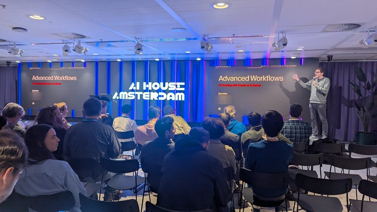 The AI House Amsterdam host on stage with the Advanced Workflows title slide on both screens before the talk