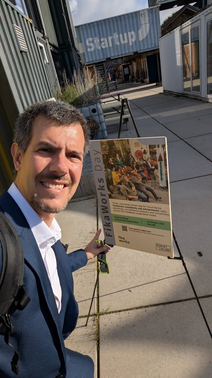 Selfie of Luca Berton next to the FikaWorks Day poster outside Startup Village, with the Startup Village lettering on the building behind