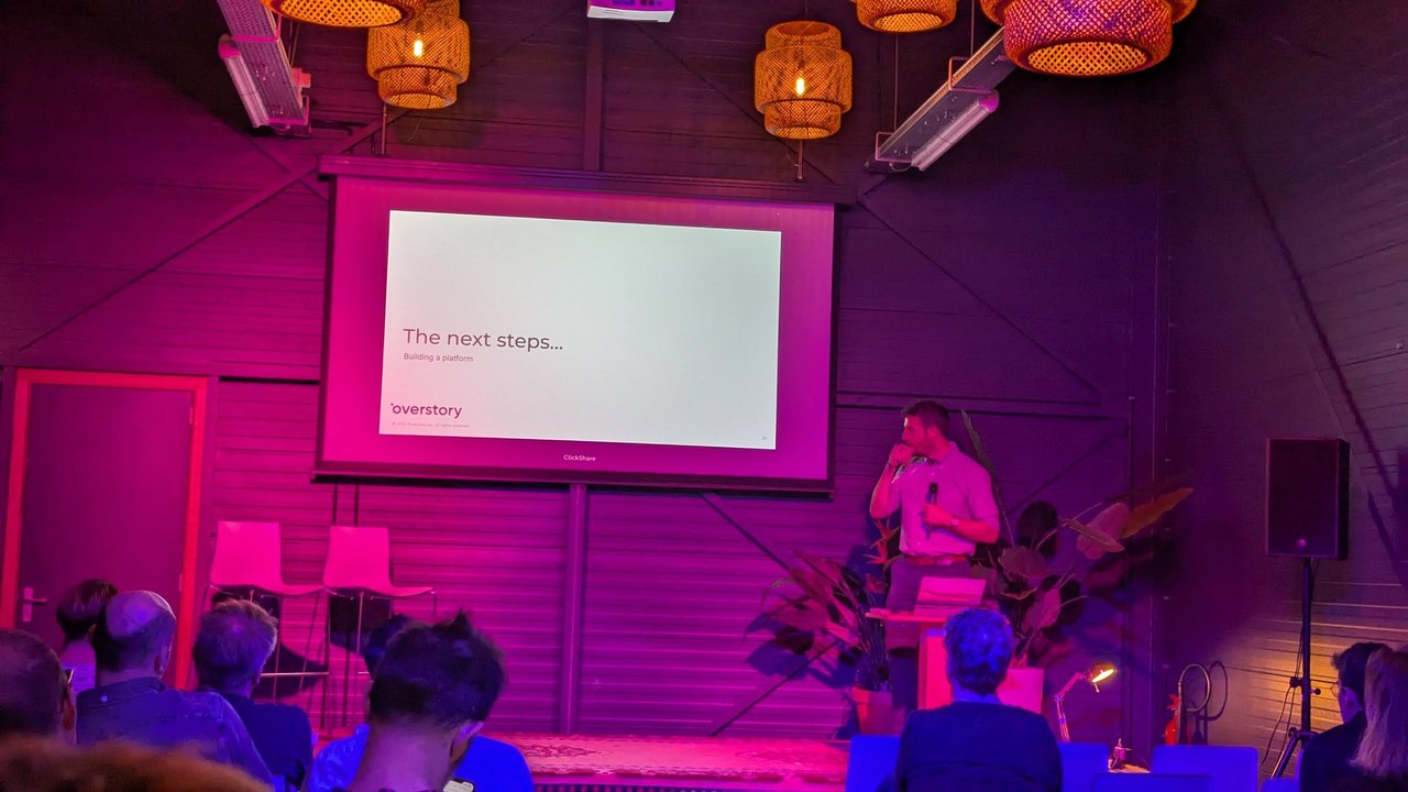 Slide titled The next steps, subtitled Building a platform, with the Overstory logo, while the speaker pauses on stage